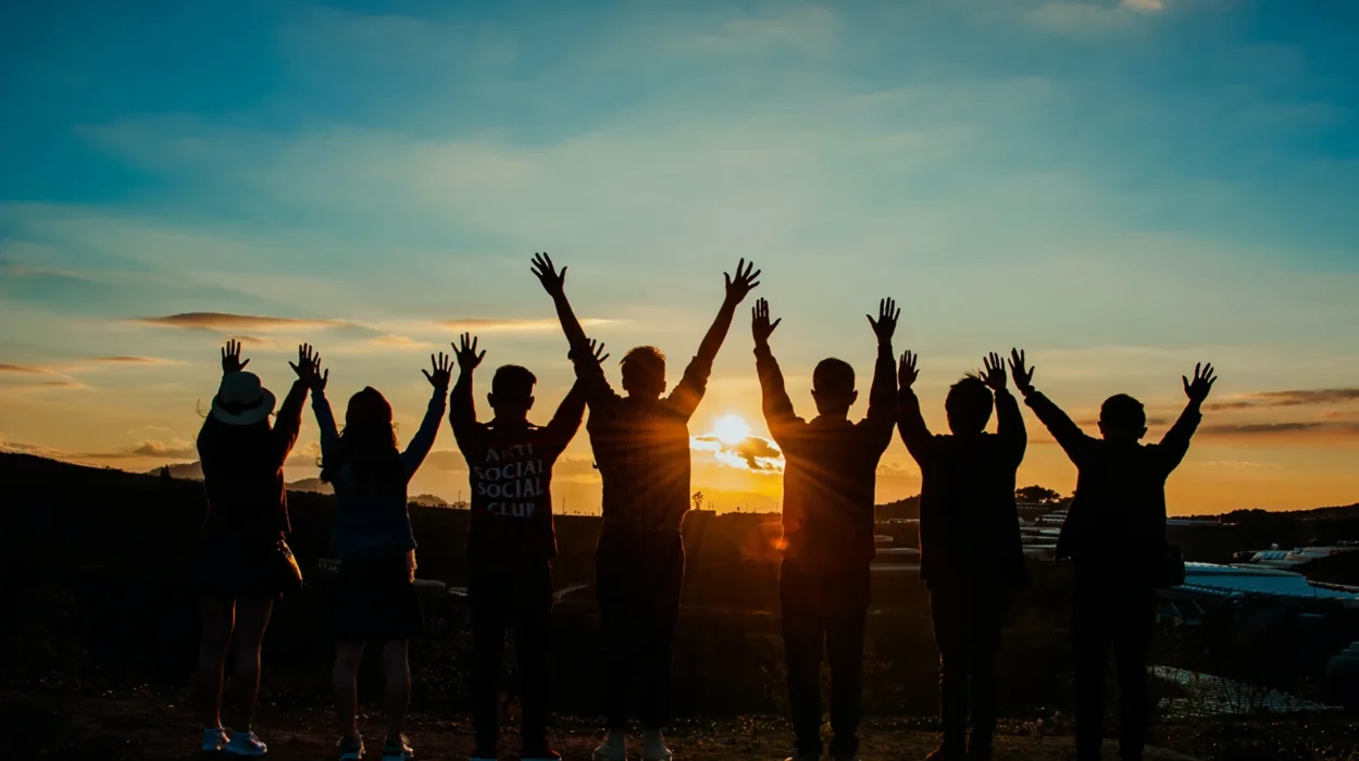 Group of people raising their arms at sunset