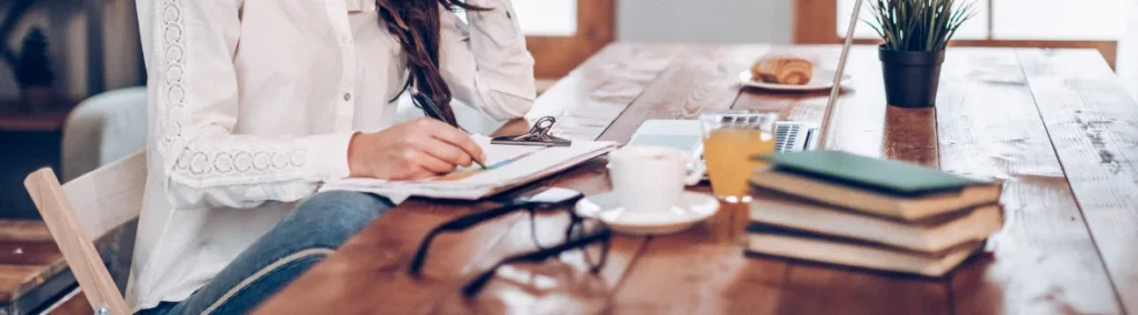 Mujer estudiando en un escritorio con libros, café y portátil