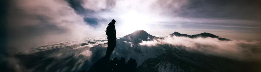 Persona en la cima de una montaña al amanecer