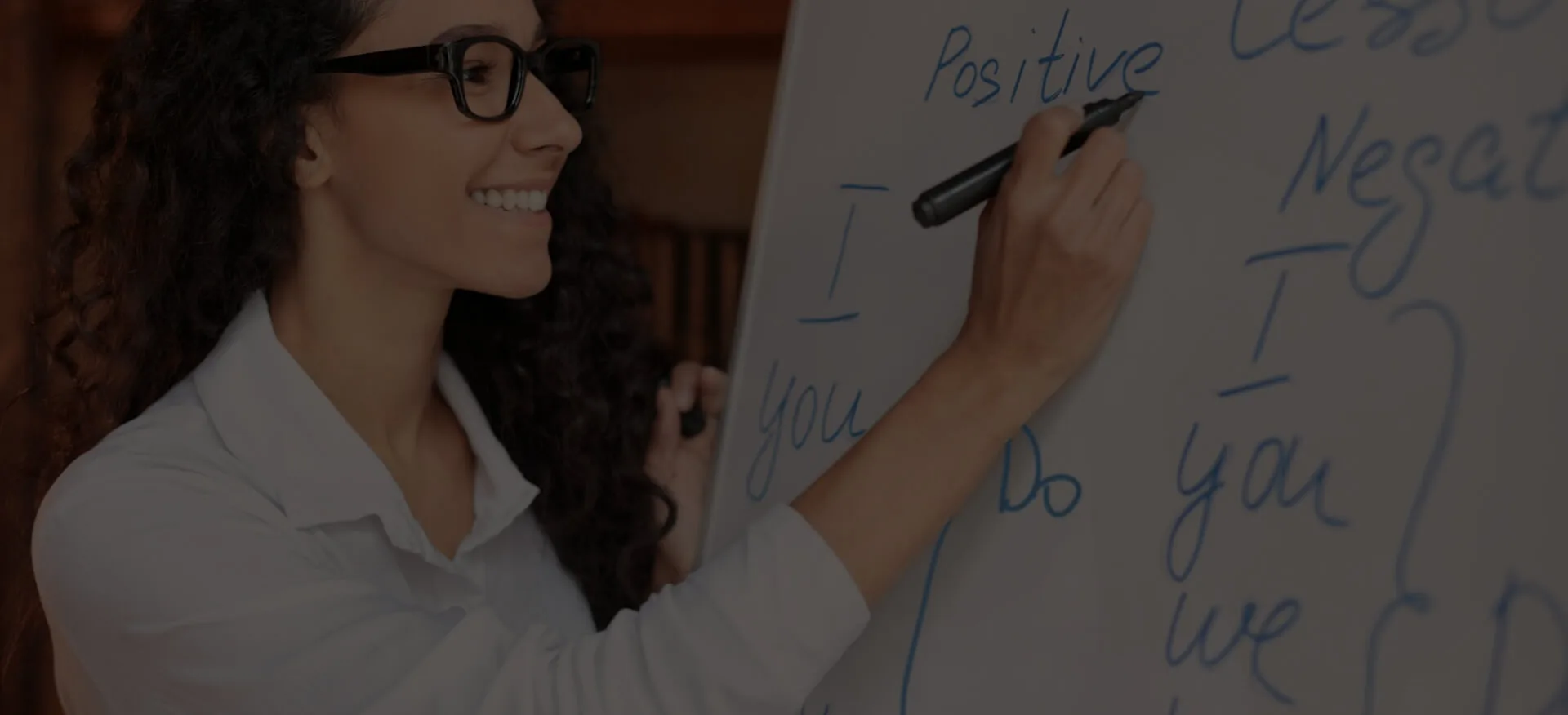 Mujer con gafas escribiendo en una pizarra blanca